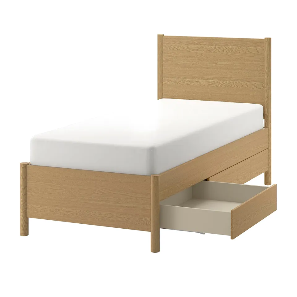 Light wooden single bed with white mattress and open bottom drawer.