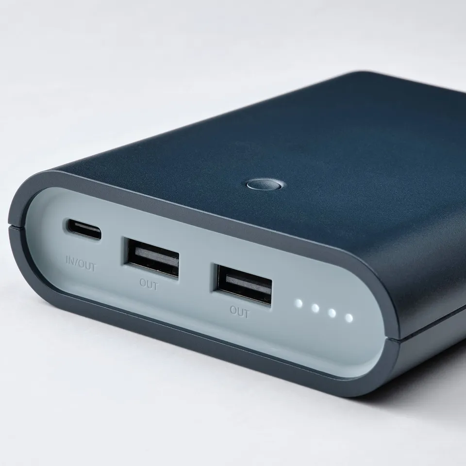 Portable power bank with 3 usb ports. Two usb-a and one usb-c. Slim, dark design with visible battery indicator lights.