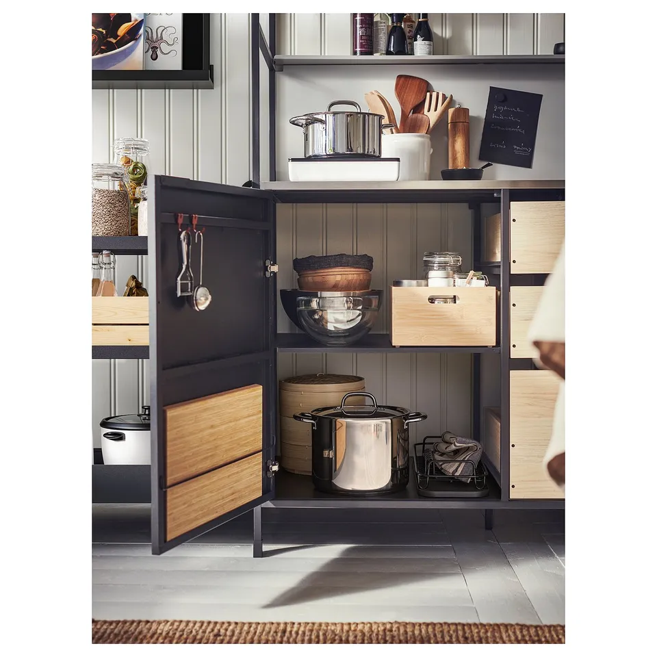 Modern kitchen cabinet with black metal & wood; open door reveals pots, pans, and cutlery; adjustable shelves.