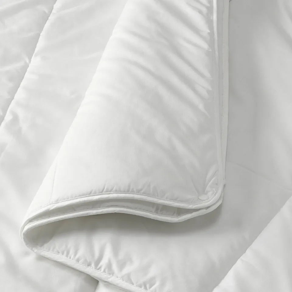 Close-up of a folded, soft, white detachable duvet. Visible stitching and smooth fabric hint at high-quality construction.