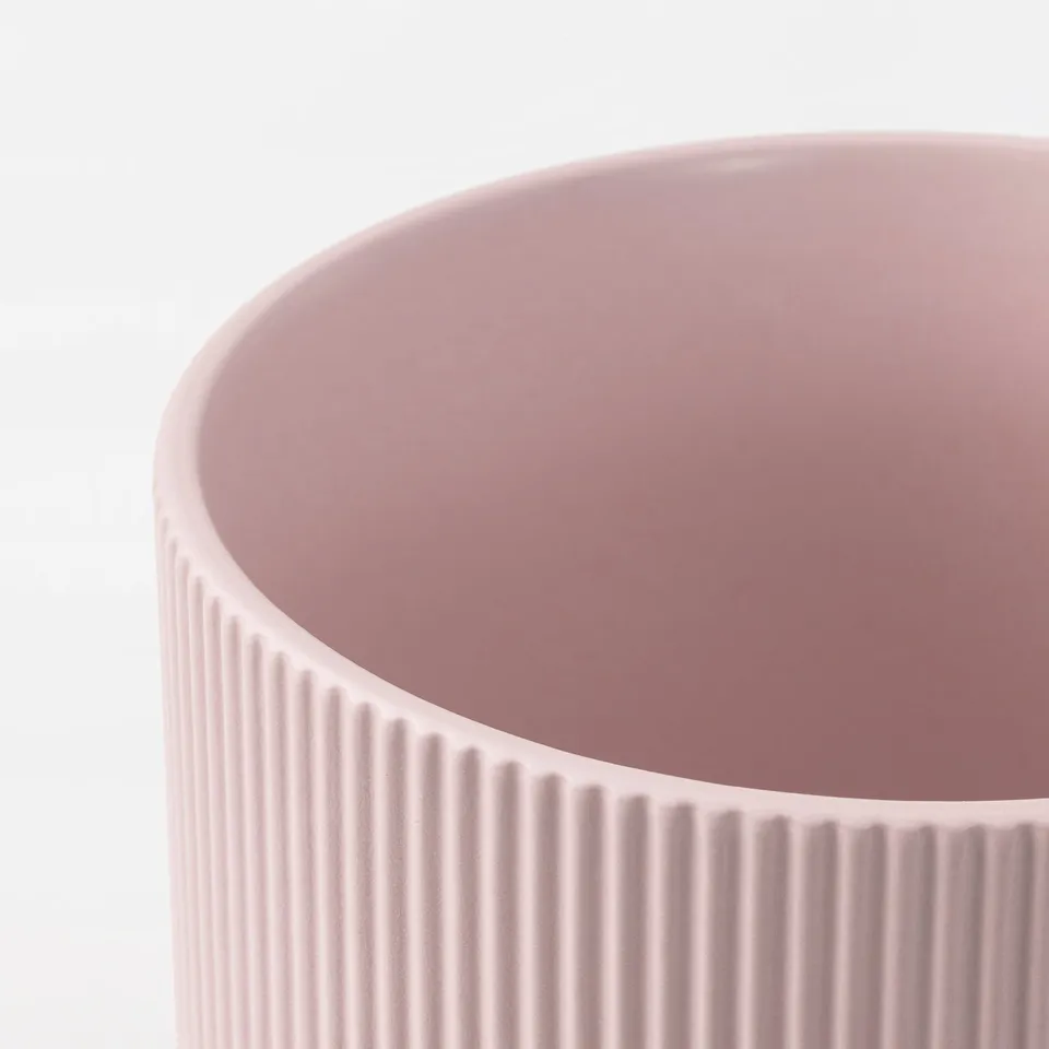 Close-up of a pastel pink stoneware vase with vertical grooves. Soft, smooth surface, high-quality craftsmanship.