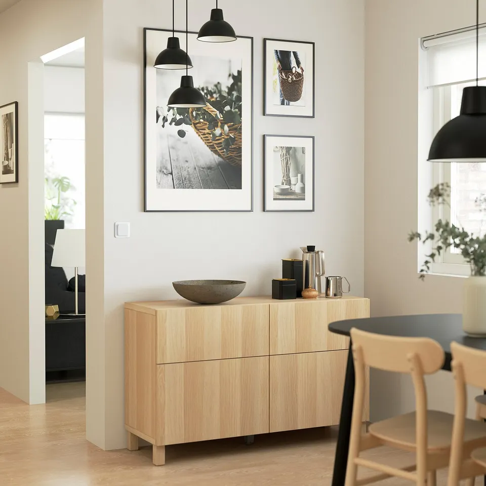 Modern dining room with oak sideboard, artwork, chairs, pendant lights.