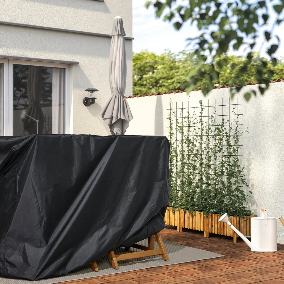 Covered patio table and chairs, umbrella, white watering can, plants.