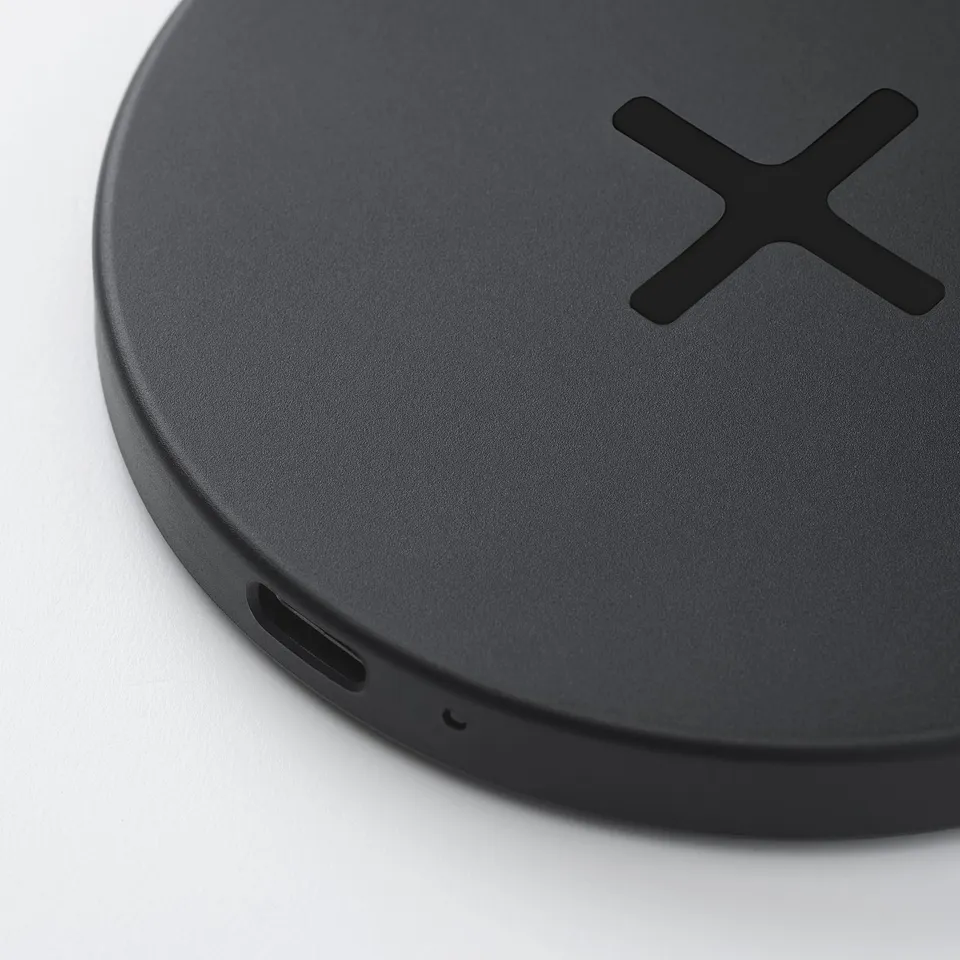 Round wireless charging pad with usb-c port and small feet for stability.