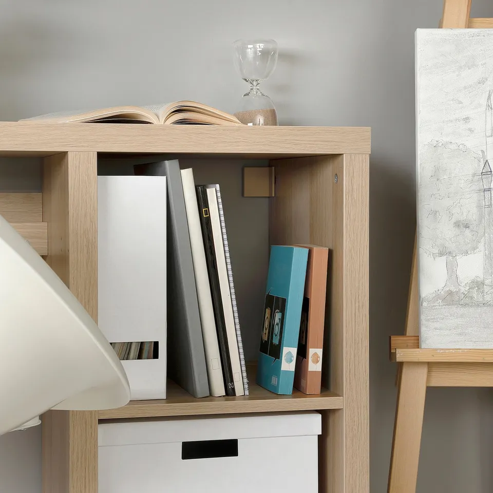 Wooden shelf with books, boxes, vase, and easel.