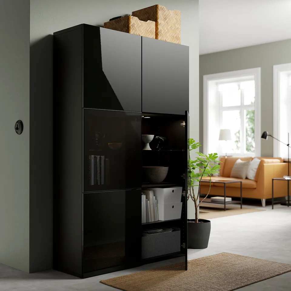 Black BESTÅ cabinet items behind glass doors, with adjustable shelves for storage.