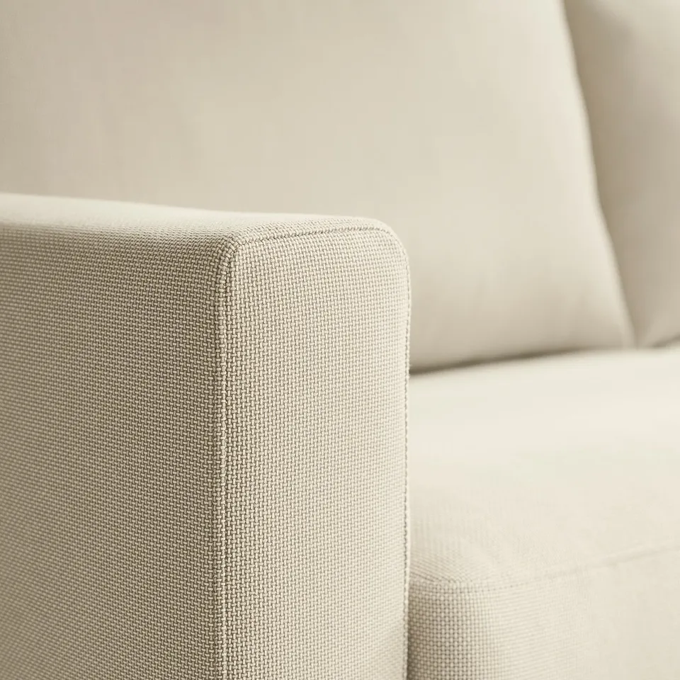 Close-up of premium, textured, beige sofa fabric showcasing detailed stitching and high-quality design.