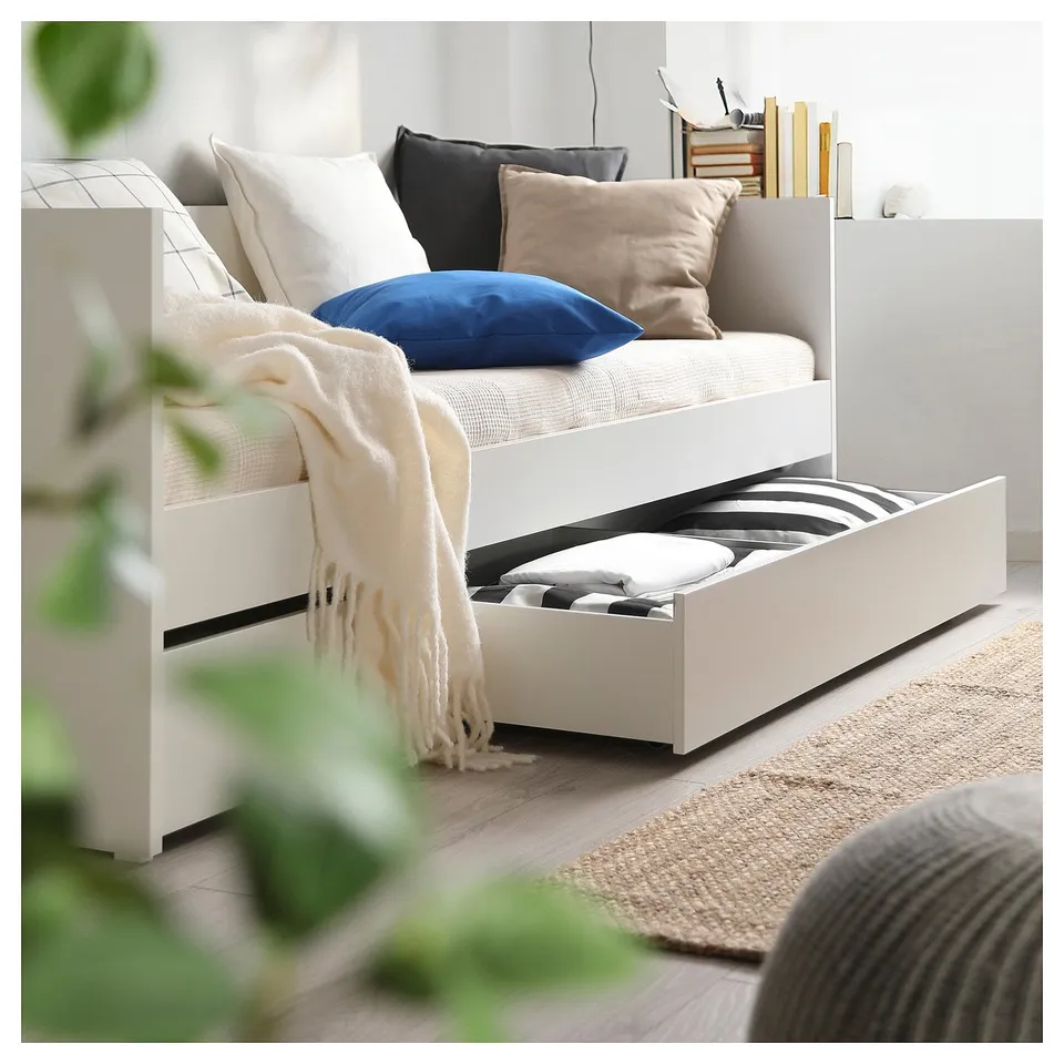 A white VIHALS daybed with storage drawers, decorated with pillows and a blanket.