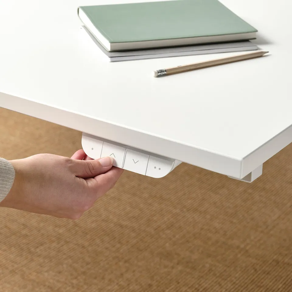 Person adjusting controls on a sit/stand desk underframe.
