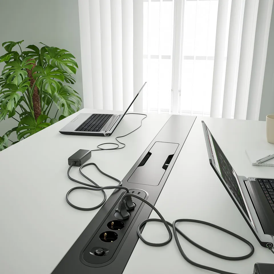 Modern conference table with power outlets and cable management, suitable for sit or stand meetings.