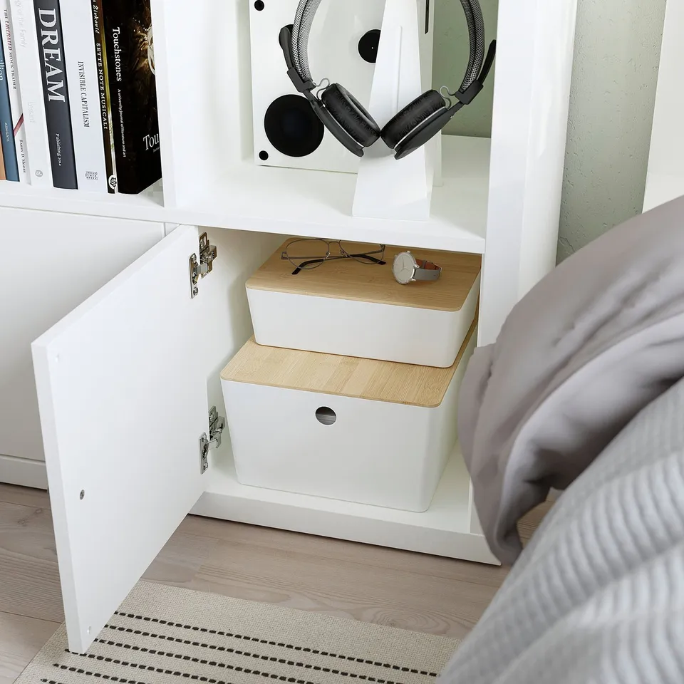 White KALLAX shelving unit with storage boxes and headphones.