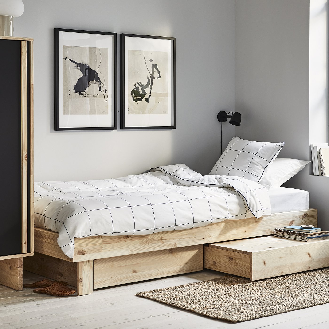 Minimalist bedroom with GLAMBERGET light wood platform bed, white grid bedding, abstract art, and wall-mounted black lamp.