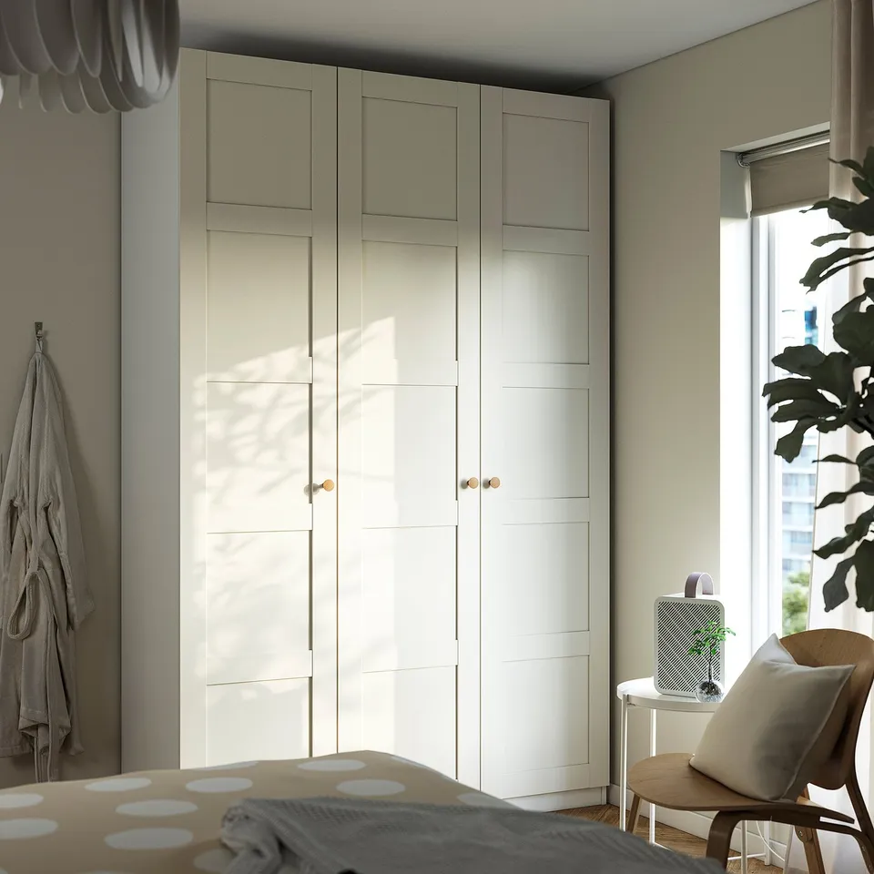 Minimalist bedroom with large white PAX wardrobe, sleek design, fitting corner, with bed and small chair.