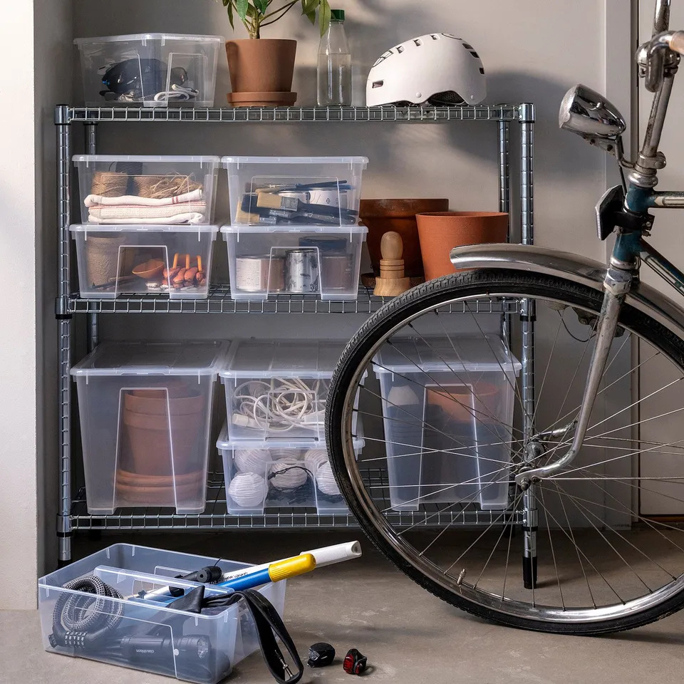 Storage system with clear boxes on a metal rack, featuring a SAMLA box with a divider beneath a bicycle.