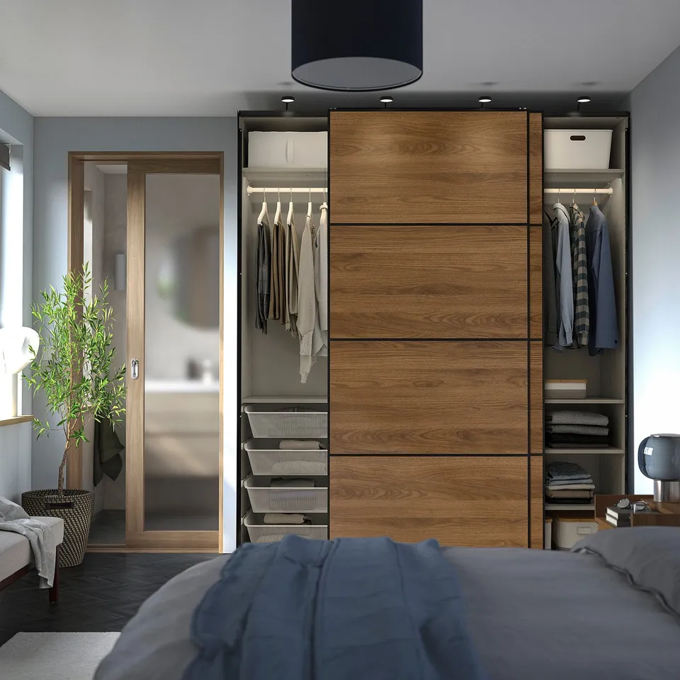 Modern bedroom with PAX wardrobe, clothes, and plant.