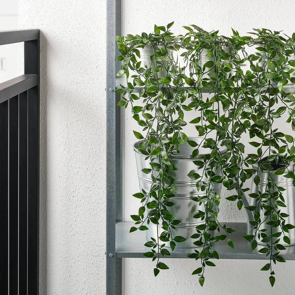 Metal rack with artificial green plants in pots.
