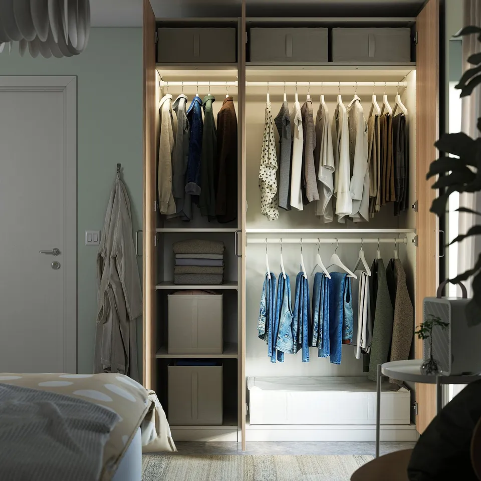 Modern, organised closet with clothes, shelves, and boxes. Integrated lighting illuminates the wardrobe.