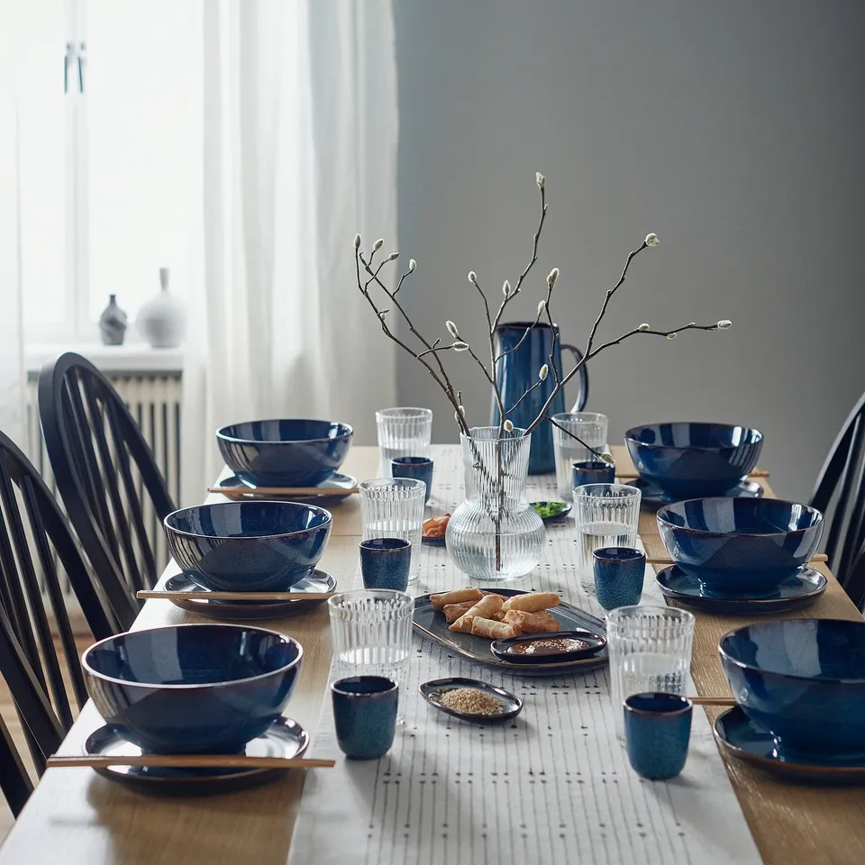 Gb: table set with GLADELIG blue bowl, stoneware for soup, centrepiece with branch, black chairs.