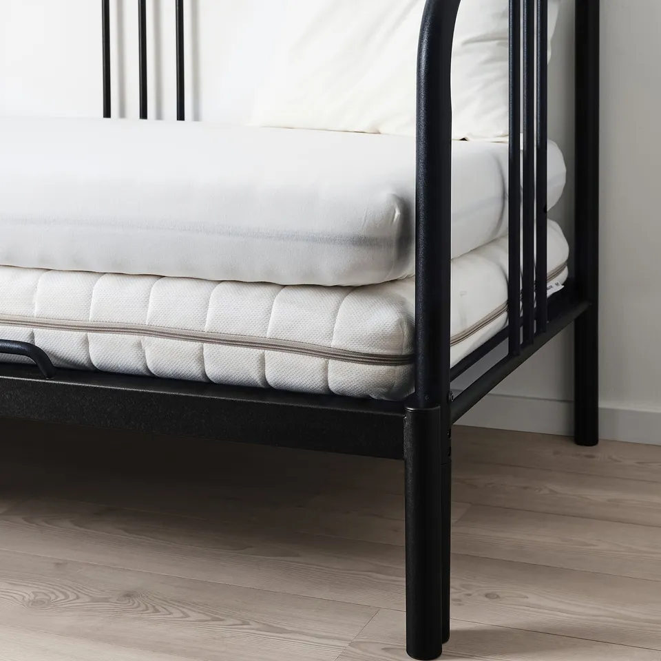 A black metal bed frame with a white mattress, showcasing the fitted sheets stretchy jersey fabric for a smooth fit.
