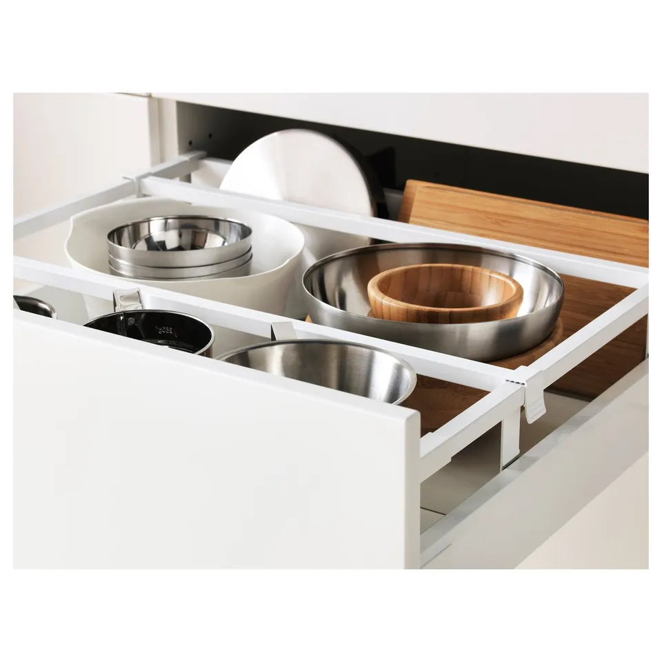Open kitchen drawer showcasing stainless steel bowls and wooden cutting boards, demonstrating organised storage and accessible design.
