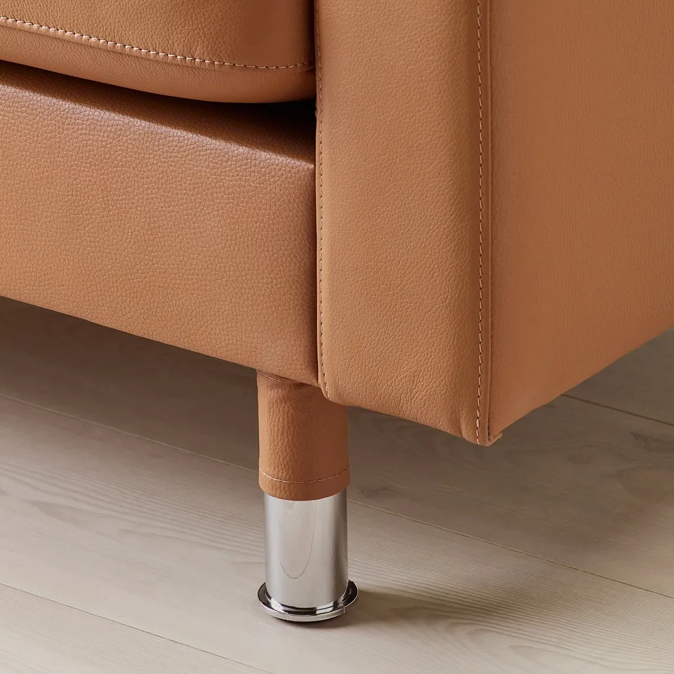 Close-up of modern leather sofa leg, polished metal base, warm-toned upholstery