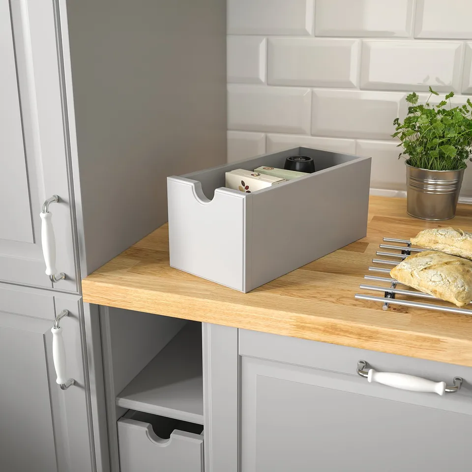 Kitchen counter with grey TORNVIKEN box, bread, and plant.