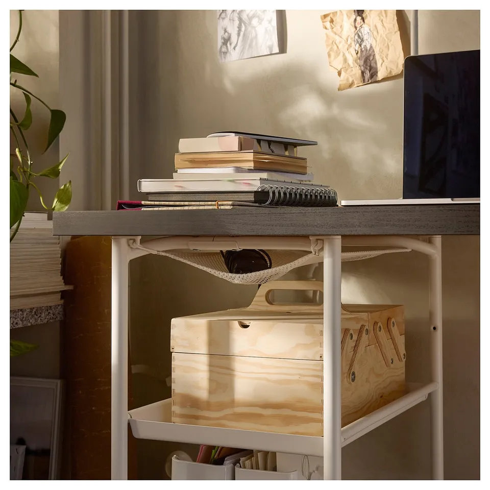 A white workspace table with shelves. It has books, a laptop, and a plant.