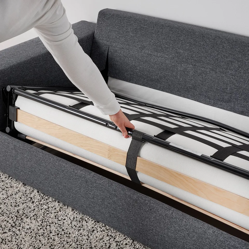 Person extends sofa-bed mechanism, transforming VIMLE sofa into a bed.
