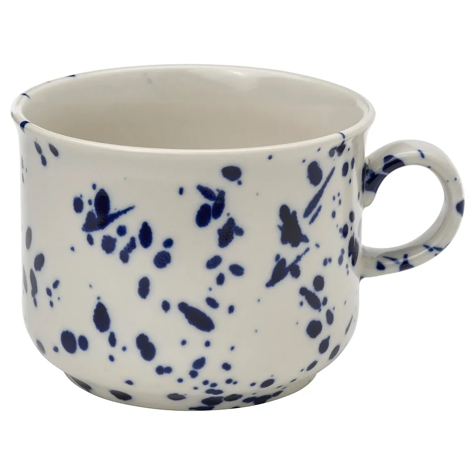 White ceramic mug with blue speckled design, handle on right side.