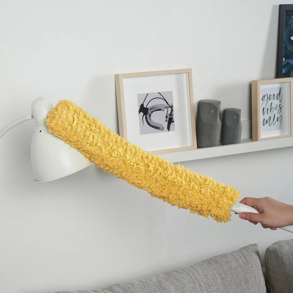 A person uses a PEPPRIG duster with an adjustable handle to clean high shelves effectively.