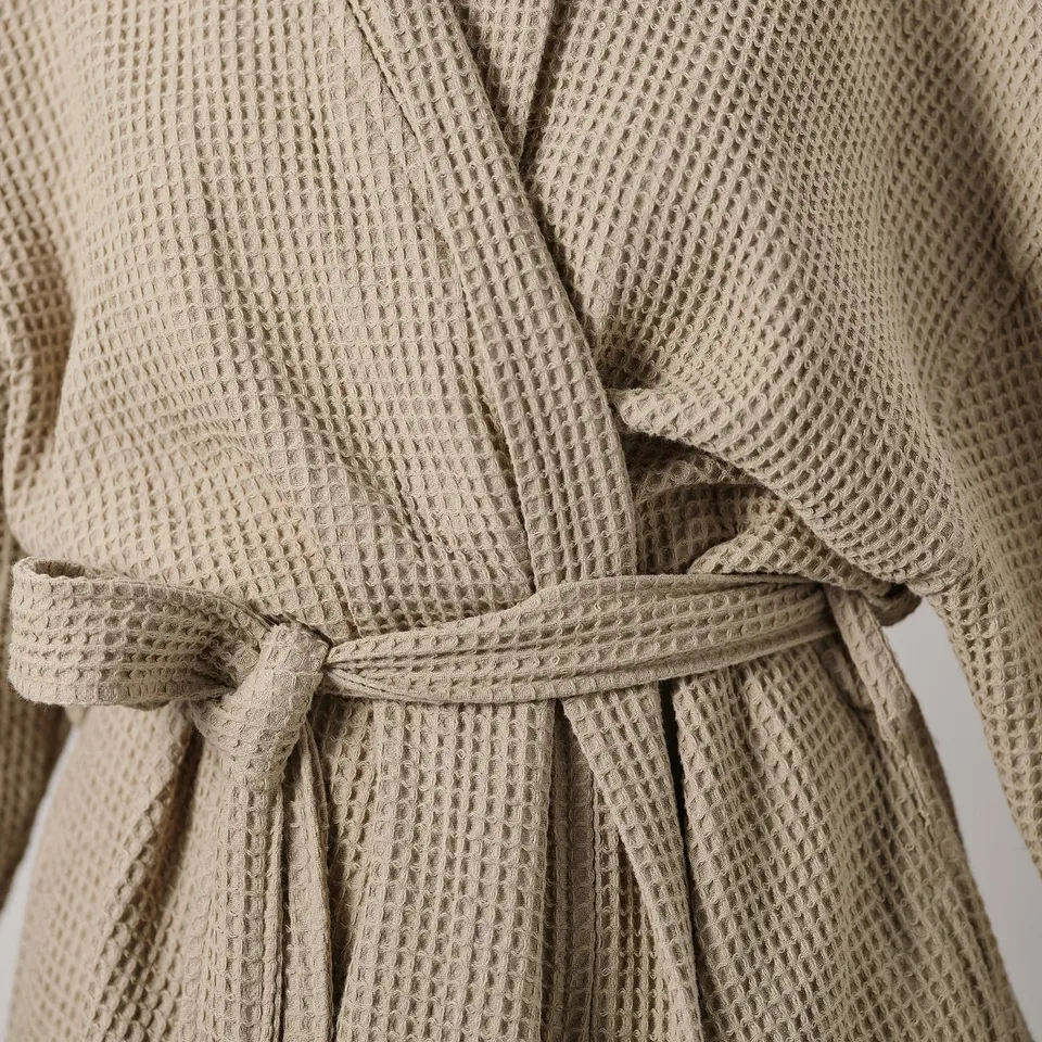 Close-up of beige robe tied with belt, featuring textured weave.