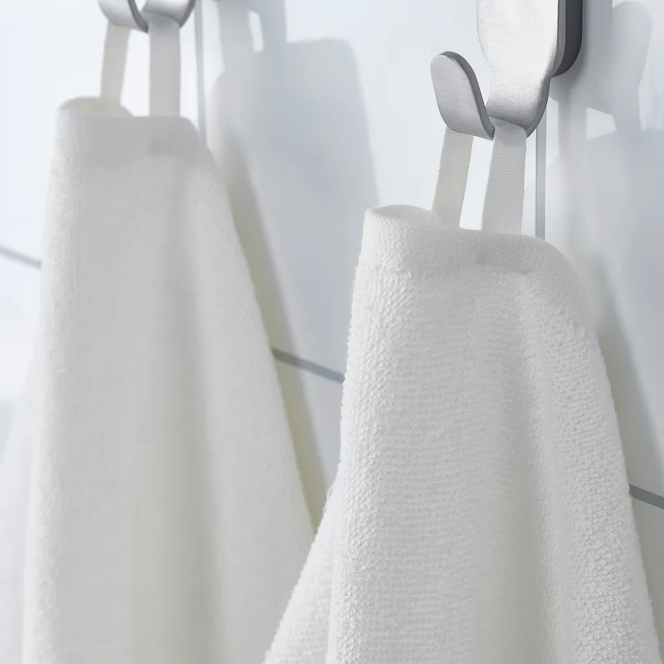 White towels hang on hooks, showcasing their lightweight and quick-drying design, ideal for travel or gym use.