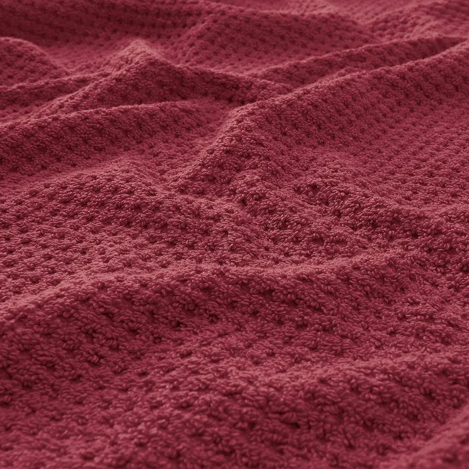 Burgundy towel, soft and fluffy texture, visible intricate weave pattern.