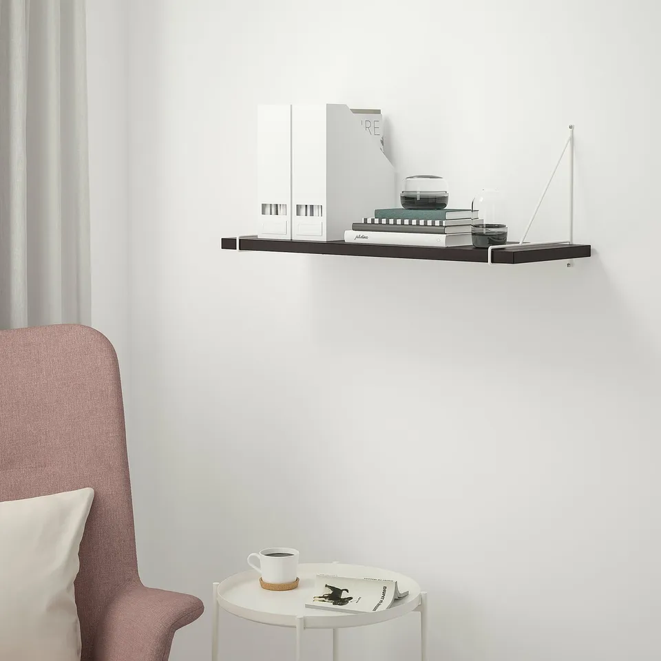 Berghsult wall shelf holds books, decor, below a side table with mug & mag, light pink chair.