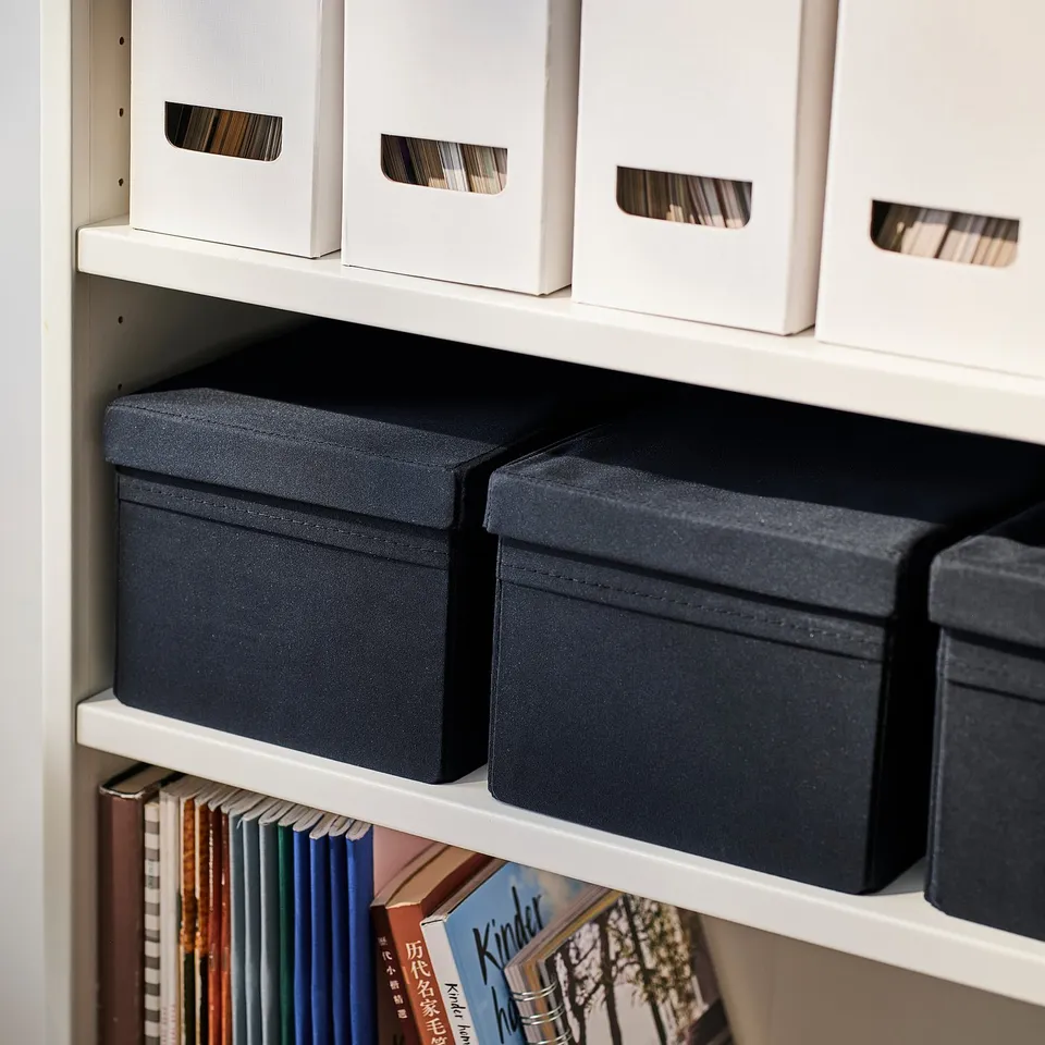 Shelf with grey fabric storage boxes and books.