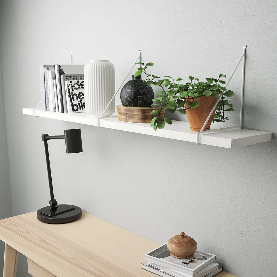 Modern desk space featuring a wall shelf holding a lamp, books, and plants.