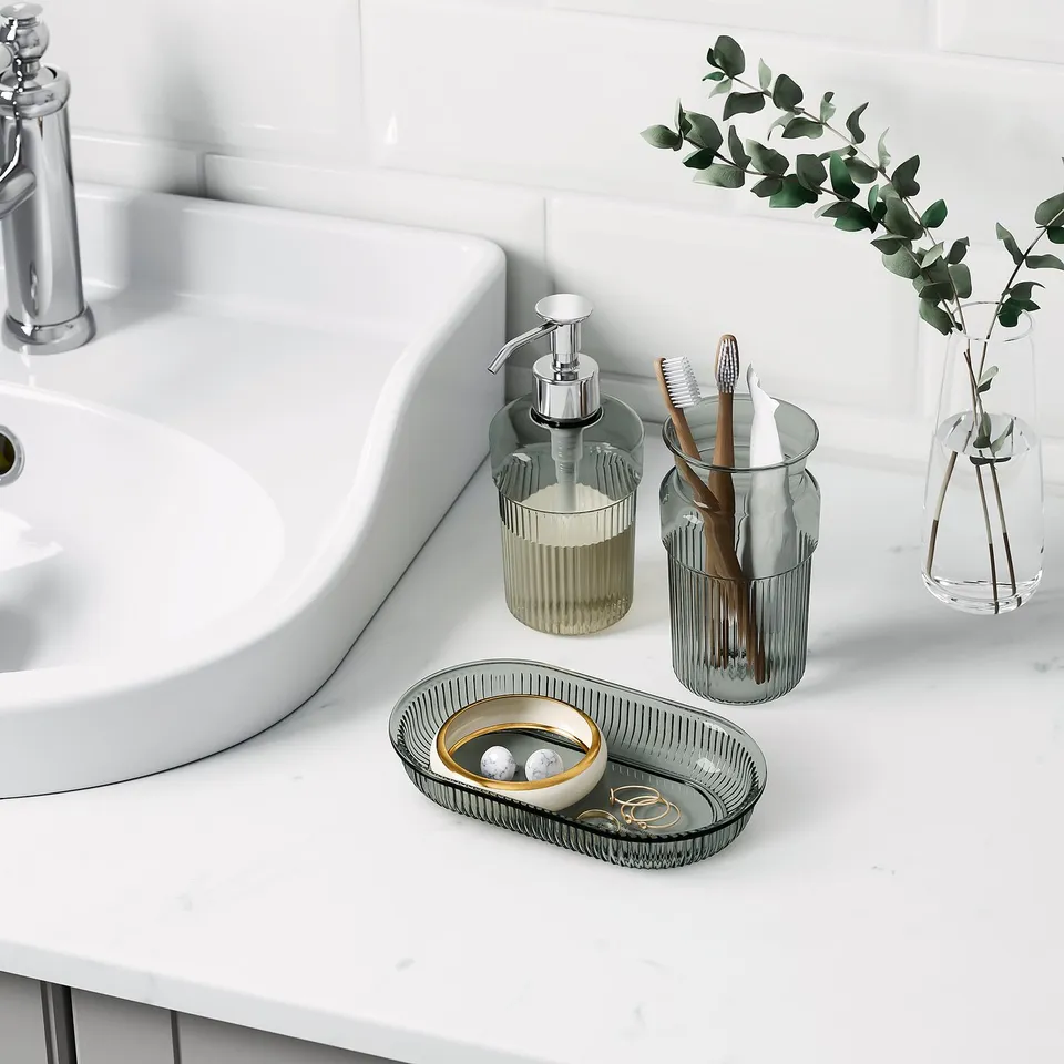 Bathroom sink with metal soap tray, dispenser, and toothbrush holder.