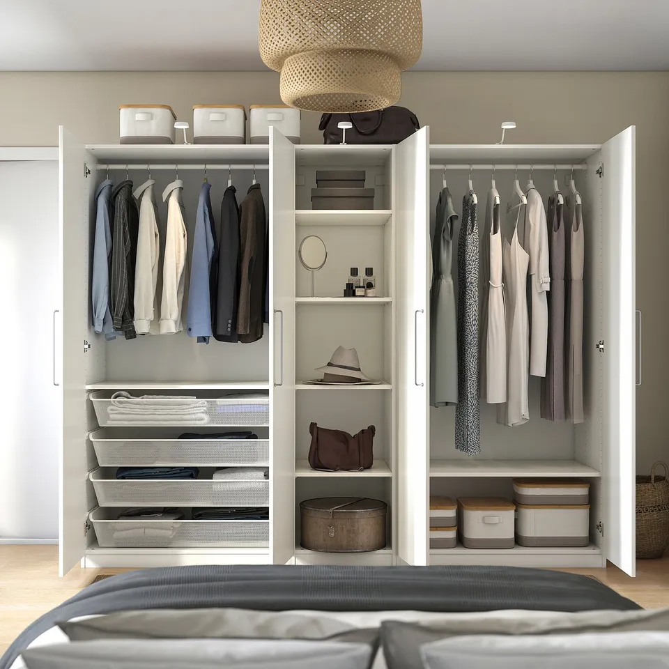 Open white wardrobe with clothes hangers, shelves, and storage boxes. Modern bedroom closet, neatly organised with various items.