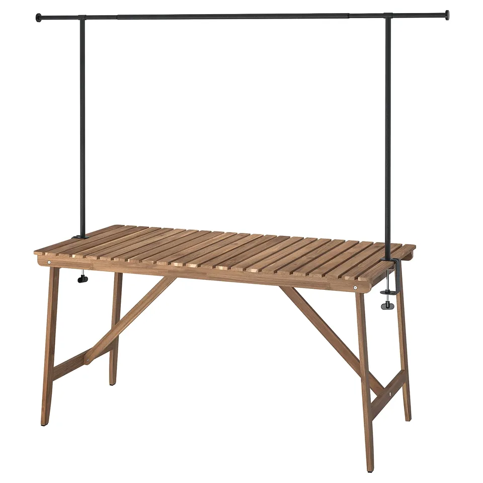 An ASKHOLMEN outdoor table with a black decorating rod. Its made of light brown acacia wood. The design is simple and functional.
