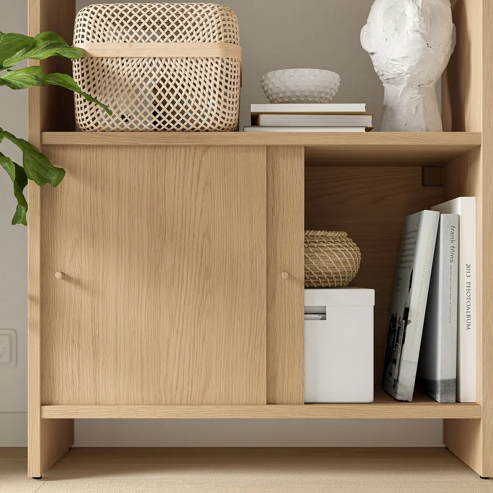 Wooden cabinet with sliding doors, featuring wicker basket, books, and statue on top.