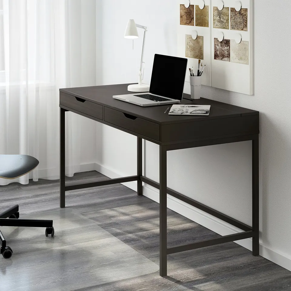 Black ALEX desk, minimalist, sleek surface, built-in drawers, metal frame, against wall, smaller than window and chair.
