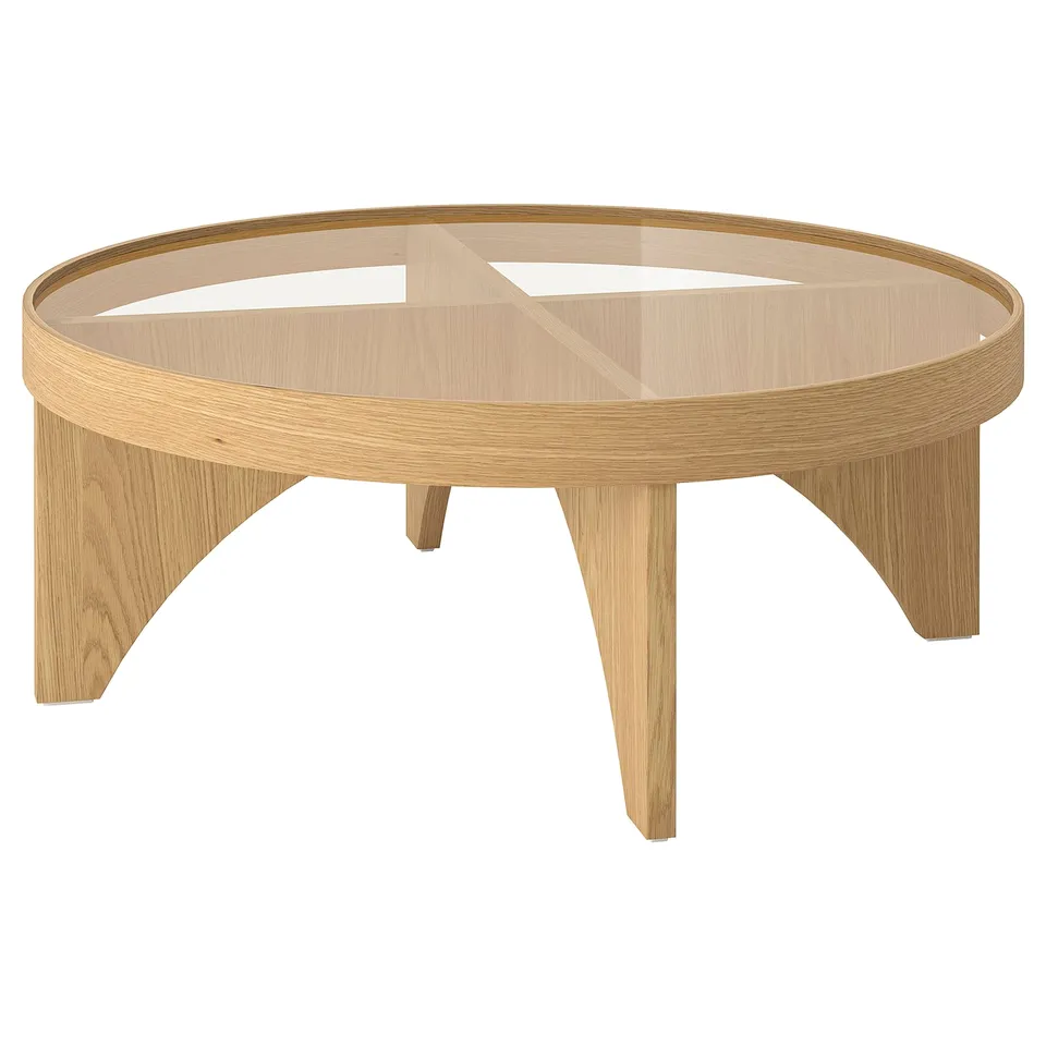 A STOCKHOLM 2025 coffee table with a light oak veneer frame and glass top, featuring a modern scandinavian design, round shape, and clear edges.