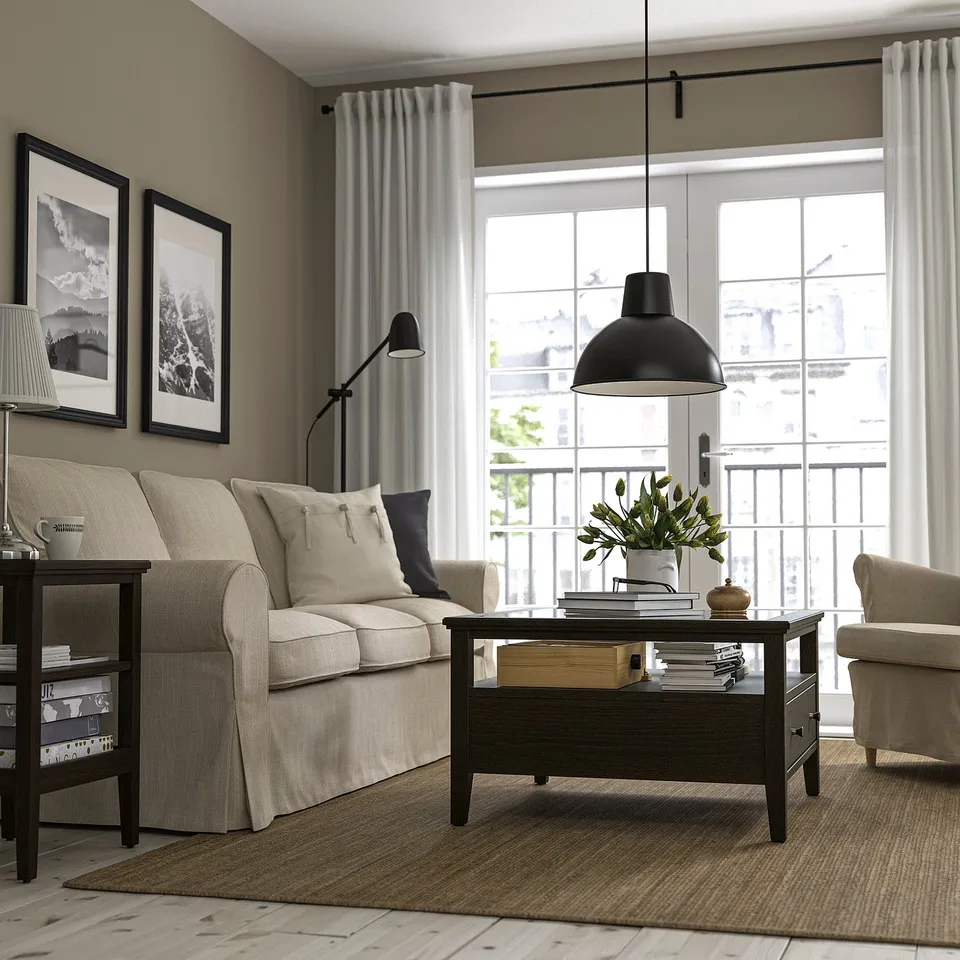 Modern living room with beige sofa, armchair, rectangular IDANÄS coffee table, and large window with white curtains.
