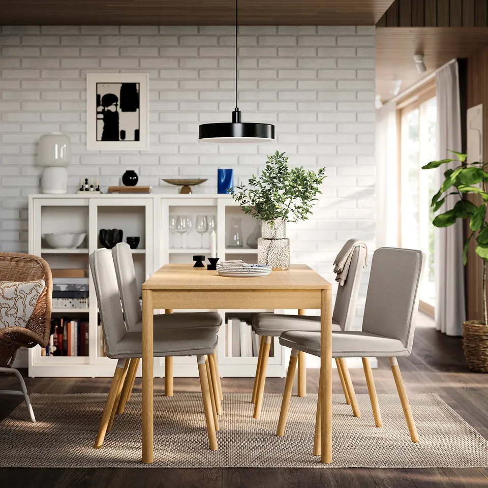 Modern dining area with TONSTAD chairs, light wood table, white brick wall, black pendant light, and greenery. Chairs fit neatly under the table.