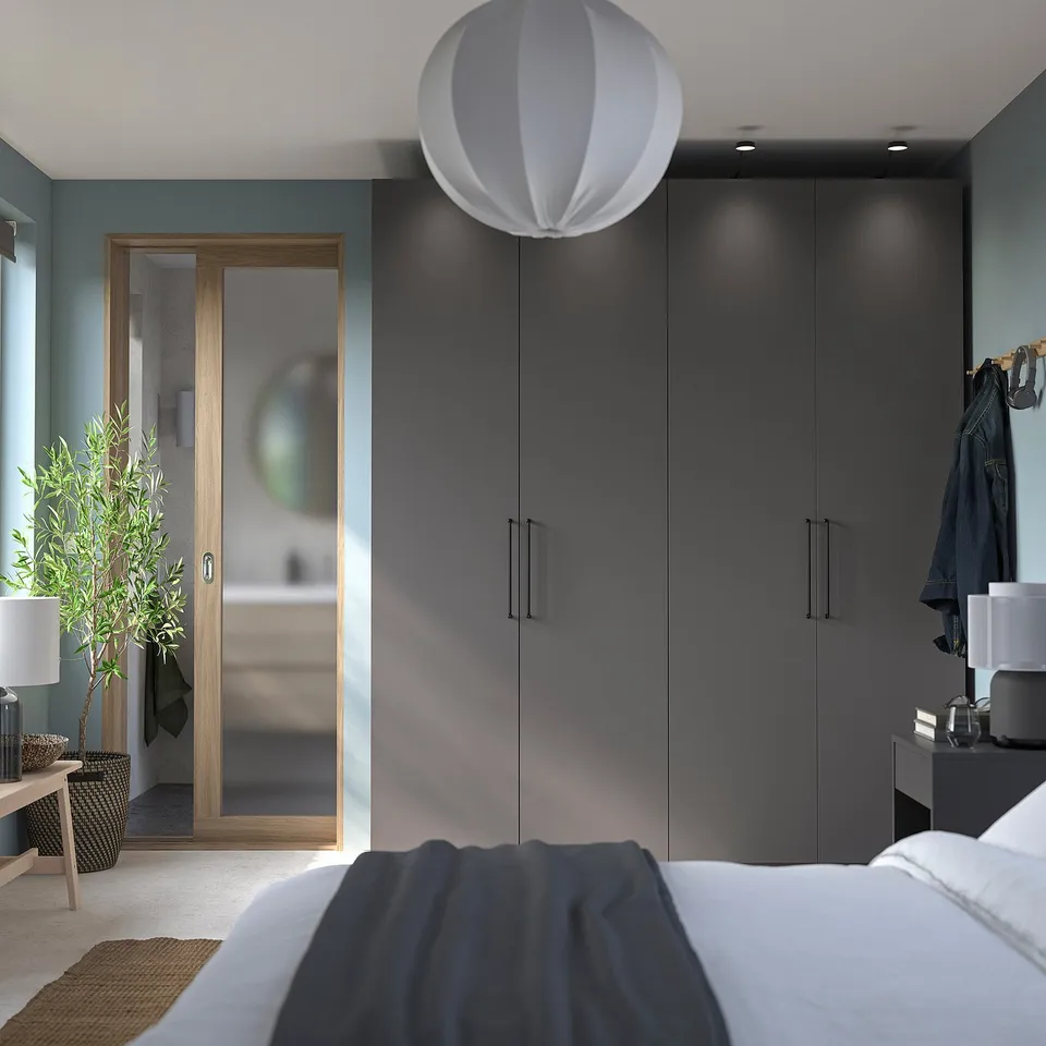 Modern bedroom with grey PAX wardrobe, white bed, and hanging plant.