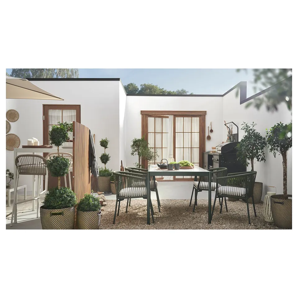Modern patio with SEGERÖN table, chairs, plants, gravel, white walls, large windows.