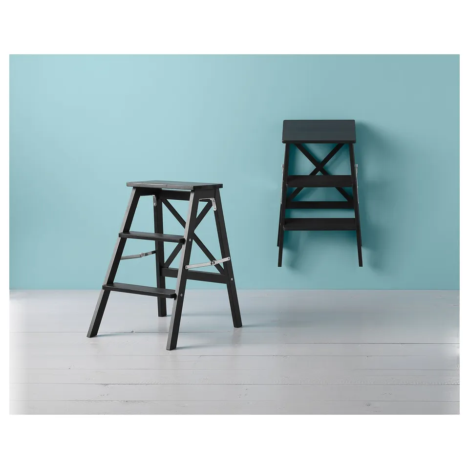 Two black folding step ladders against a blue wall on a white floor.