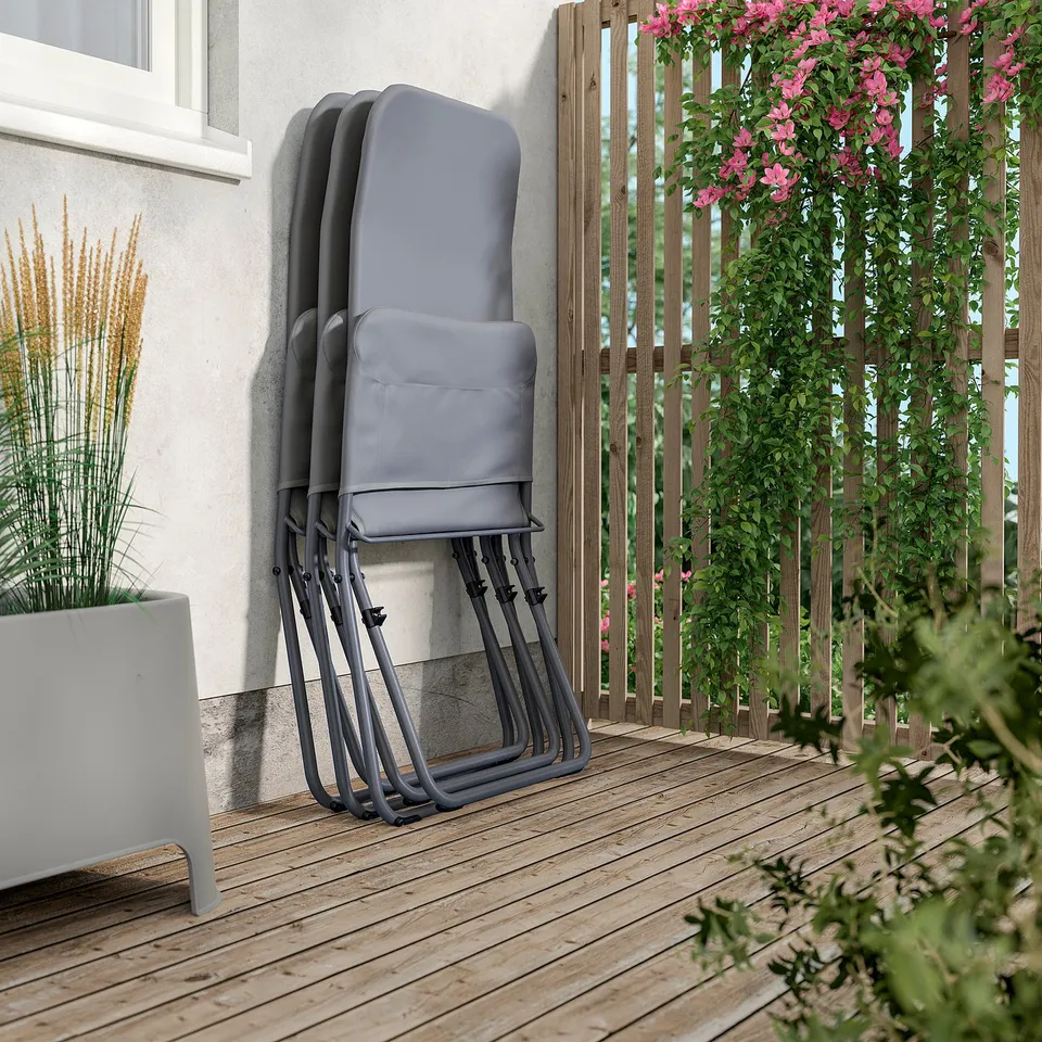 Stacked grey foldable lounge chairs on wooden deck by white wall and planter.