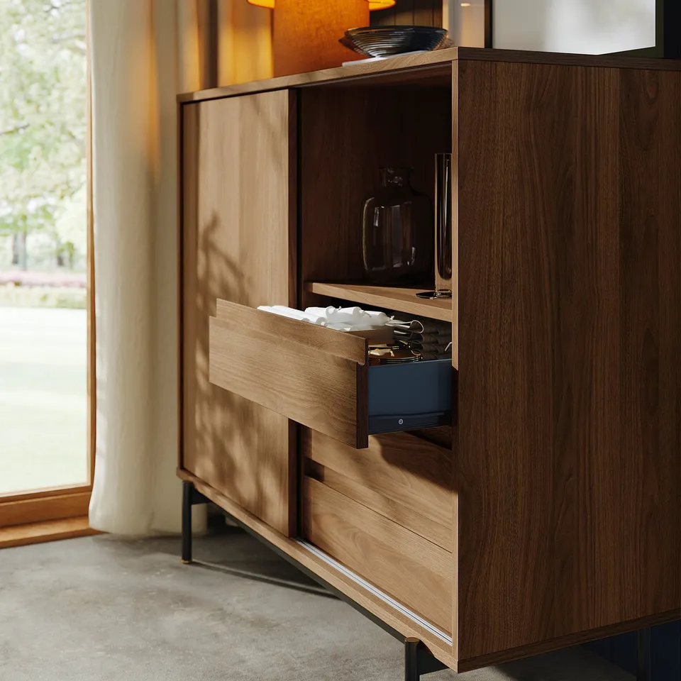 Wooden cabinet with sliding doors revealing drawer of cutlery and hidden microwave.