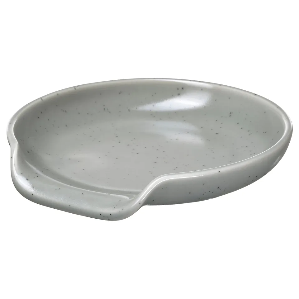 White RÖDSYRA ceramic spoon rest with dotty glaze, oval shape, ergonomic handle.